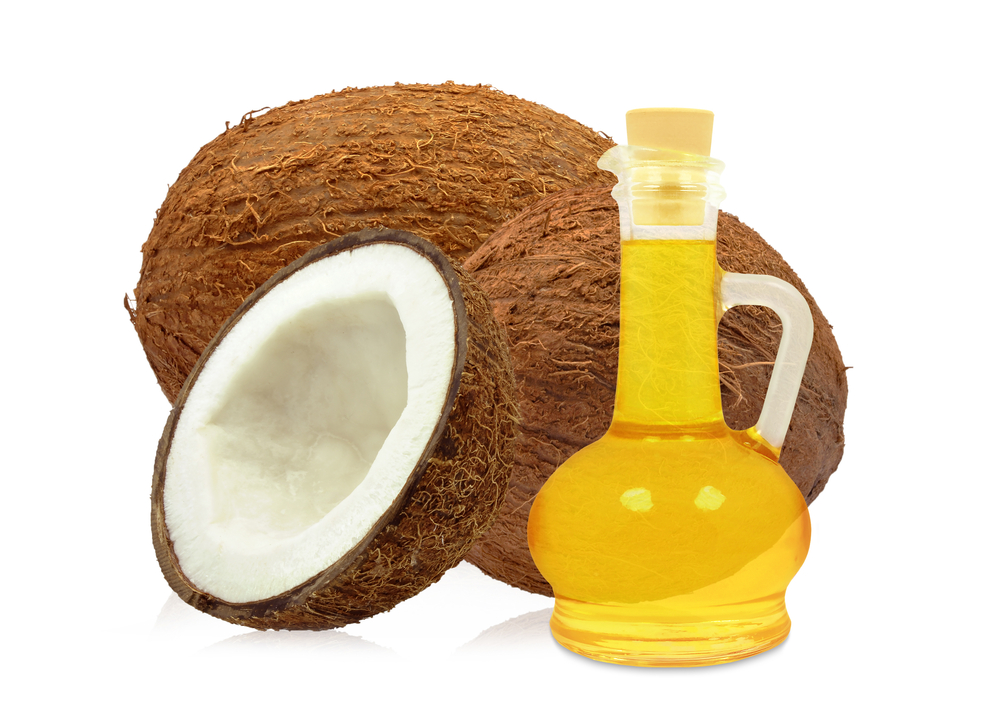 Noix de coco aux côtés d'une vieille fiasque d'huile