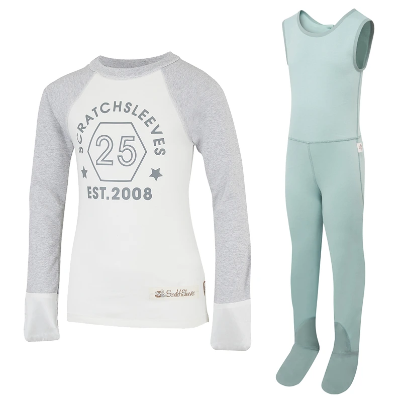 Vue de face du haut de pyjama ScratchSleeves de style baseball avec coutures extérieures au niveau des épaules, du cou et de l'ourlet. Corps blanc avec logo imprimé gris représentant un hexagone et est.2008. Encolure et manches en marron gris, avec mitaines blanches cousues. Corps en coton 100% et mitaines en soie naturelle 100%. Étiquette externe et marquage sur le côté gauche vers la base du haut. Vue de face de la salopette ScratchSleeves seafoam sans couture intérieure de jambe et avec les pieds cousus. Pieds fermés avec une couche de coton tissé gris 100% sur le devant du pied et sous l'orteil. Corps sans manches en jersey de coton 100% vert seafoam, bordé d'un liseré de coton tissé gris sur le bras et l'encolure.