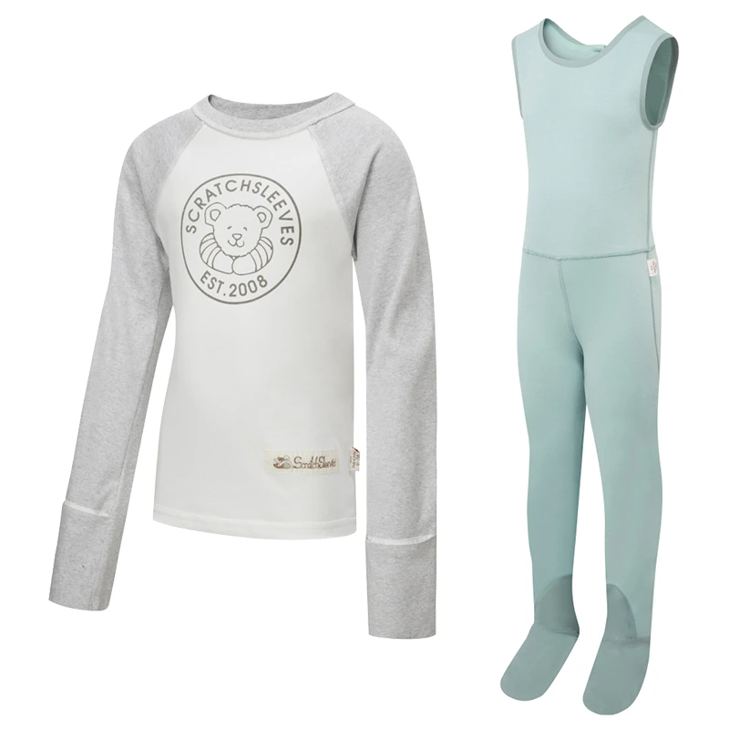 Vue de face du haut de pyjama ScratchSleeves pour enfants, style baseball, avec coutures extérieures aux épaules, à l'encolure et à l'ourlet. Corps blanc avec logo sérigraphié gris représentant un ours et est.2008. Encolure et manches en marron gris, avec les moufles repliées sur elles-mêmes. Corps en coton 100% et mitaines en soie naturelle 100%. Étiquette externe et marquage sur le côté gauche vers la base du haut. Vue de face de la salopette ScratchSleeves pour enfants, sans couture intérieure de la jambe et avec les pieds cousus. Pieds fermés avec une couche de coton tissé gris 100% sur le devant du pied et sous l'orteil. Corps sans manches en jersey de coton 100% vert seafoam, bordé d'un liseré de coton tissé gris sur le bras et l'encolure.