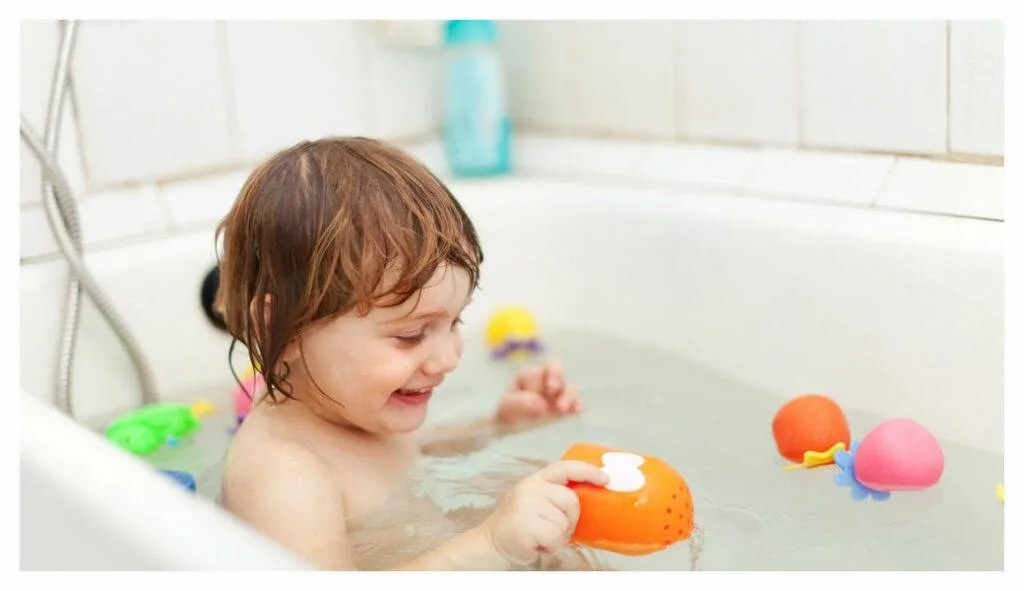 Enfant en bas âge dans son bain, jouant avec des jouets en plastique aux couleurs vives. L'heure du bain pour les enfants atteints d'eczéma n'est pas synonyme de bulles !