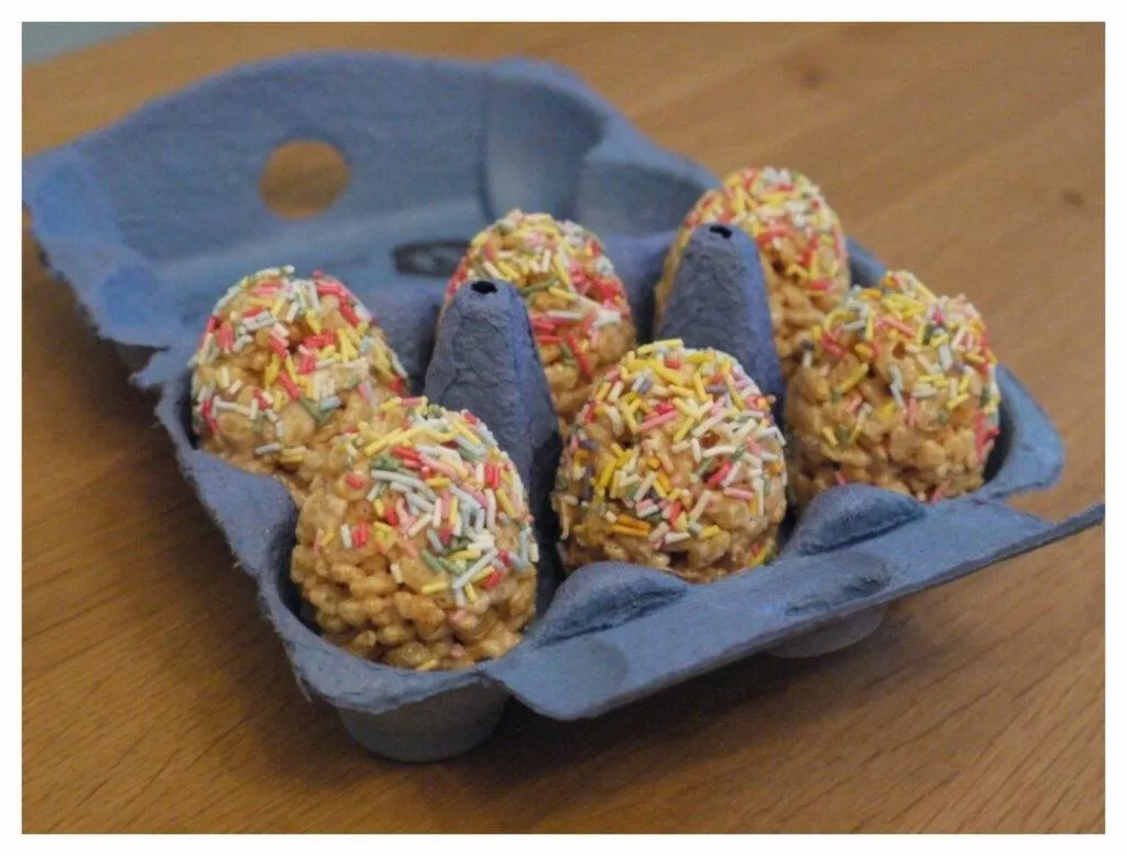 Geöffnete Eierschachtel mit Ostereiern aus Reiskrispies und Marshmallows, umhüllt von bunten Zuckerfäden
