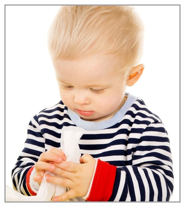 Toddler body looking intently at the bay wipe in his hands
