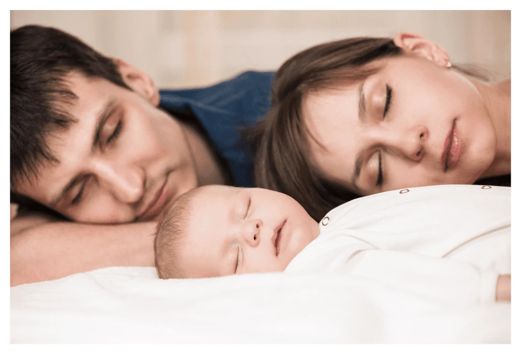 parents dormant profondément avec un jeune bébé devant eux. Il s'agit manifestement d'une mise en scène, étant donné le maquillage parfait de la maman !