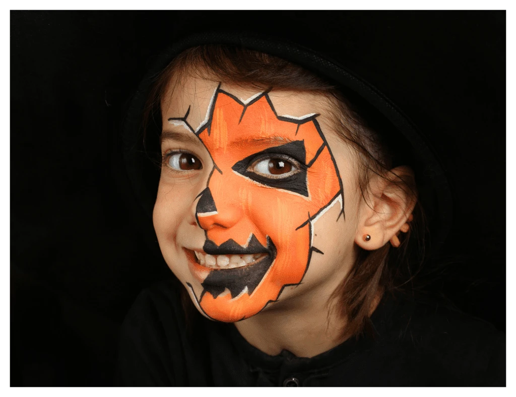 Girl with orange and black Halloween face paint and a huge smile