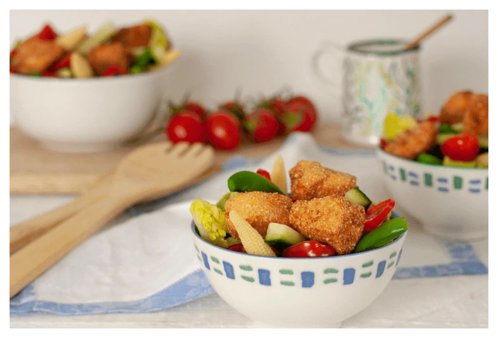 Ekzemerfreundliche knusprige Lachshäppchen, serviert auf einem gemischten Salat aus Tomaten, Gurken, Babymais und Paprika