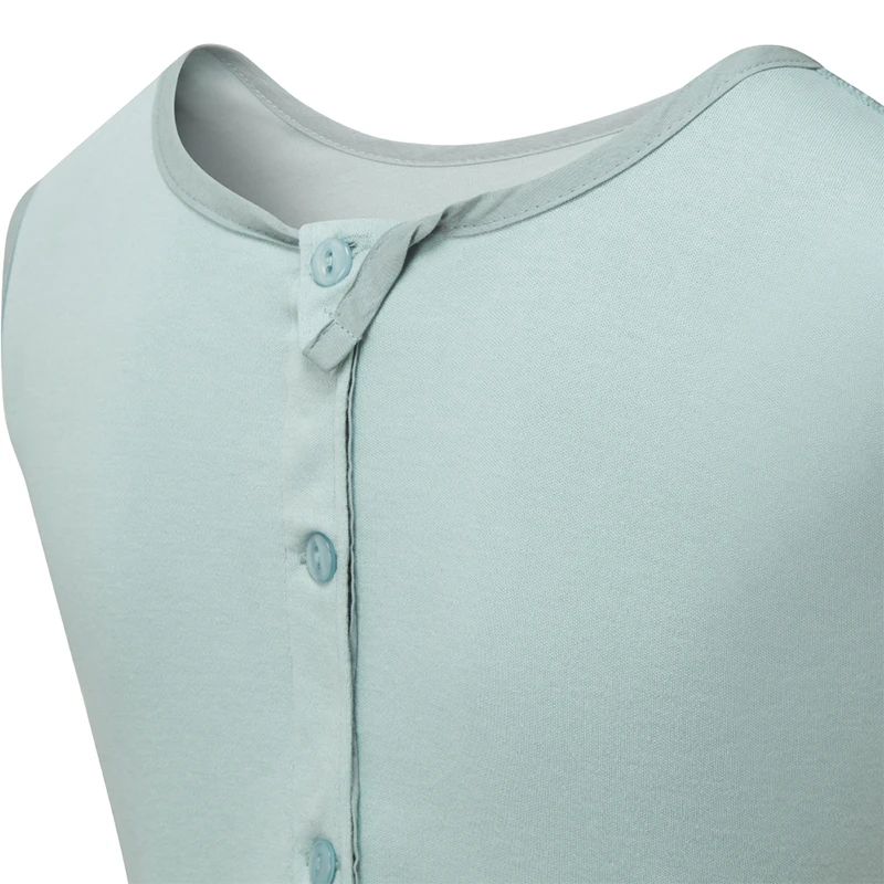 Vue rapprochée de l'arrière de la salopette ScratchSleeves Seafoam pour enfants, montrant l'ouverture renforcée dans le dos, du cou vers le bas, avec les boutons verts qui la maintiennent fermée. Bouton supplémentaire à droite avec fermeture à boucle et patte supplémentaire qui se replie sur l'encolure avec fermeture à bouton pour la maintenir en place. Corps sans manches en jersey de coton 100%, de couleur vert d'eau, avec garniture en coton tissé gris au niveau de l'encolure.