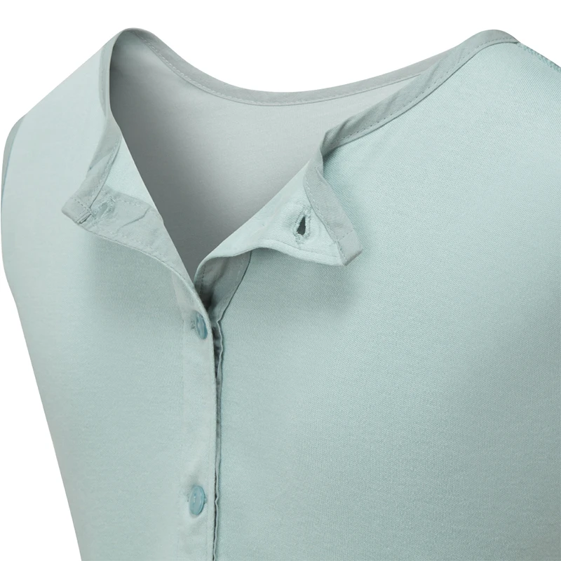 Vue rapprochée du dos de la salopette pour enfants ScratchSleeves, montrant l'ouverture renforcée dans le dos, du cou vers le bas, partiellement ouverte avec des boutons verts à droite et des trous et une boucle pour les boutons à gauche. Une patte supplémentaire à droite avec une boutonnière se replie sur l'encolure et se ferme à l'aide d'un bouton pour la maintenir en place. Corps sans manches en jersey de coton 100% de couleur vert mousse, avec garniture en coton tissé gris au niveau de l'encolure.