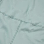 Gros plan sur une salopette sans couture pour enfants. Le gros plan montre la couleur crème, le tissu en coton et la couture extérieure au niveau de la taille et de la béquille.