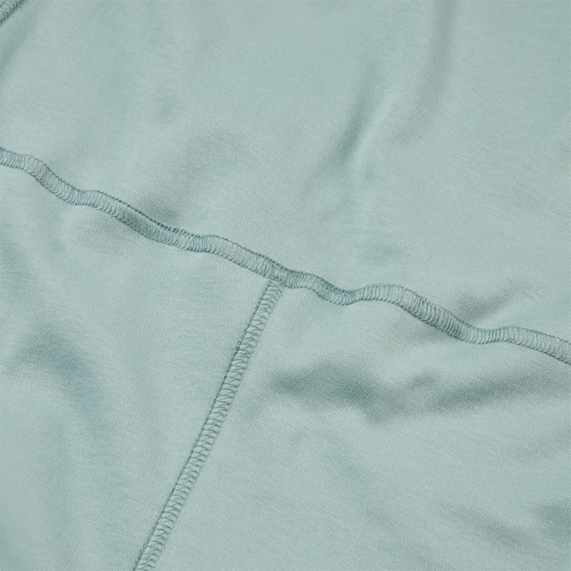 Gros plan sur une salopette sans couture pour enfants. Le gros plan montre la couleur crème, le tissu en coton et la couture extérieure au niveau de la taille et de la béquille.