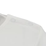 Gros plan sur les poppers au niveau du cou du pyjama ScratchSleeves "Sleepy Bear" pour enfants. Haut de pyjama en jersey de coton 100% sans colorant blanc avec des boutons-pression blancs. L'encolure peut être élargie pour ne pas traîner sur les visages endoloris et elle est très sûre une fois bouclée.